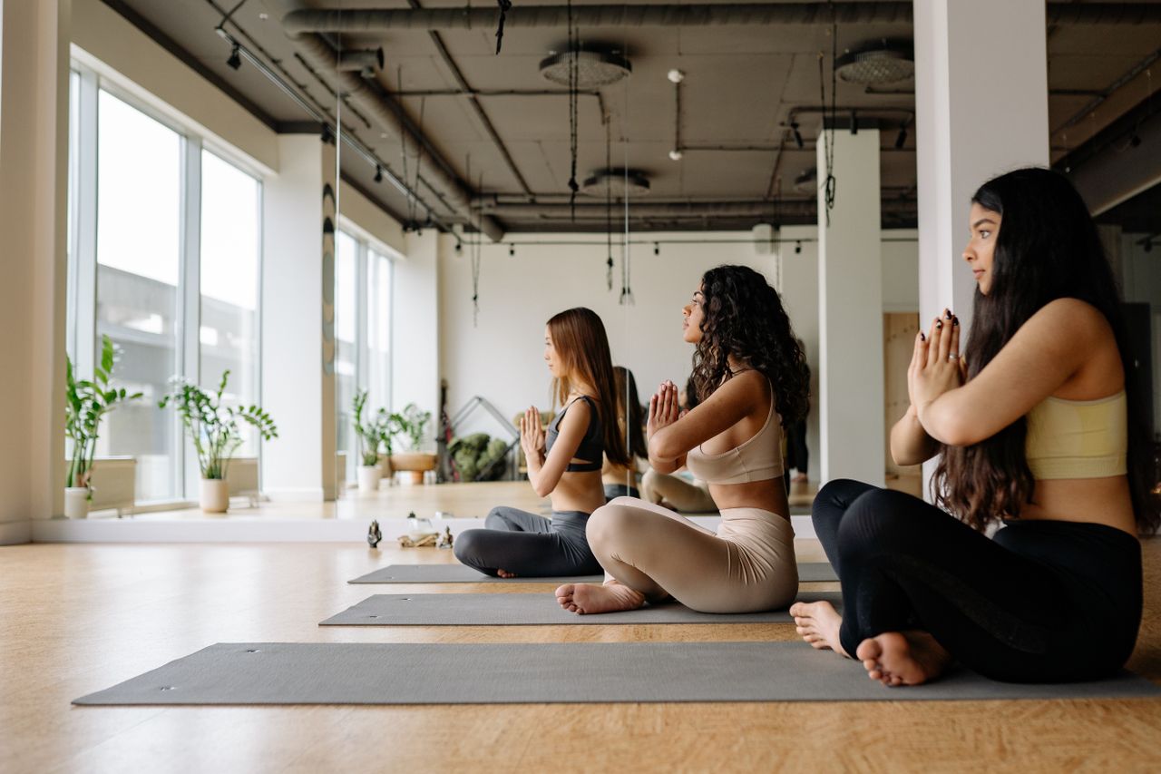 Group of women focused on meditation and yoga pose in a modern indoor studio.
